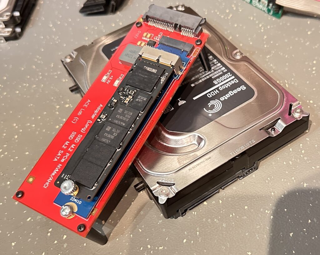 Na zdjęciu widoczny jest dysk twardy Seagate oraz adapter do dysk&oacute;w SSD M.2 NVMe. Adapter leży na tradycyjnym dysku twardym, co sugeruje przygotowanie do analizy danych lub transferu pomiędzy r&oacute;żnymi rodzajami nośnik&oacute;w. Całość jest umieszczona na powierzchni roboczej, prawdopodobnie w laboratorium technicznym.